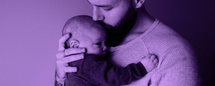 A father holding his baby, kissing it on the forehead