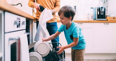 A boy putting dishes in the dishwasher as part of his chores 