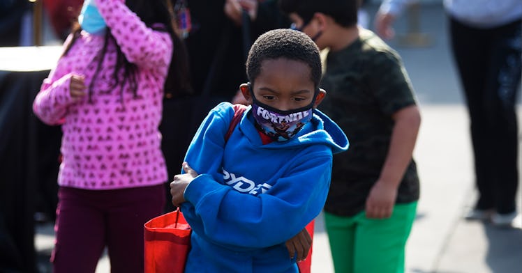 A young boy in a Blue hoodie wears Fortnite face mask