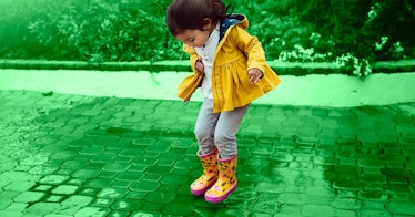 5-year-old in yellow coat jumping in a puddle as a spring activity