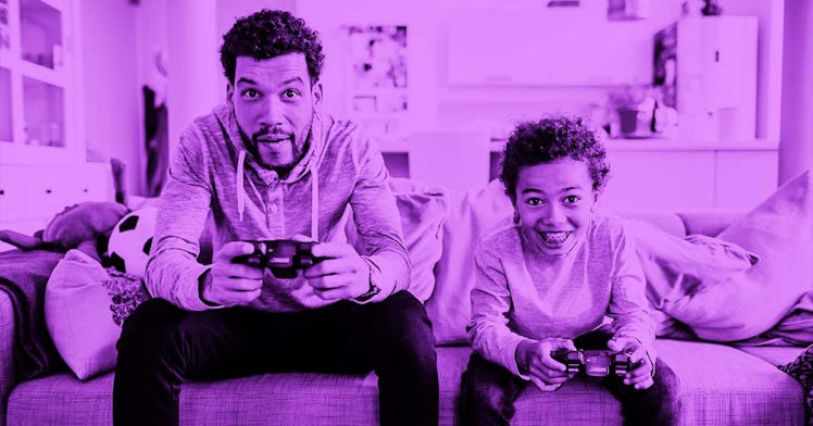 A dad and son sitting on the couch in their living room playing video games together