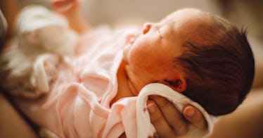 a baby being held by an adult, depicting a newborn about to be named