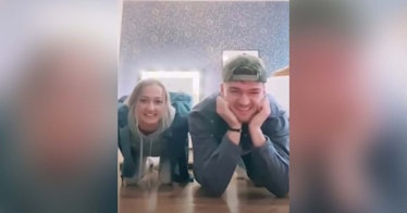 A man and woman doing the center of gravity challenge from their knees and elbows.