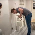 a man attempts the chair challenge at home while his wife looks on