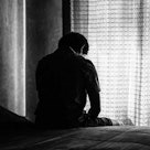 一个正在经历离婚的男人坐在床上，悲伤地看着窗外