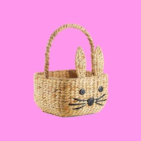 wicker Easter basket for kids with a embroidered bunny face isolated on pink background