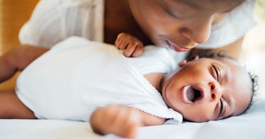 a baby girl lying on a crib being comforted by a parent, depicting a flower name for girls