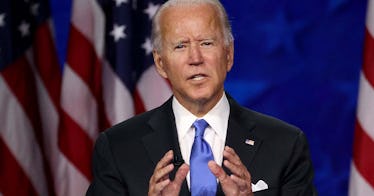 Joe Biden speaks in front of a blue background with American flags