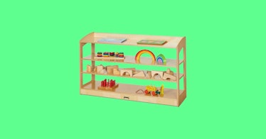 Montessori shelves, set against a green backdrop, give kids easy access to their toys and books