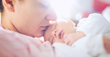 a father holds his newborn baby girl and kisses her forehead in a sunlit room that inspires nature n...
