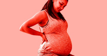 a pregnant woman experiencing bleeding during pregnancy rests her right hand on her waist as she loo...