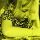 photo of child drawing with crayon at table