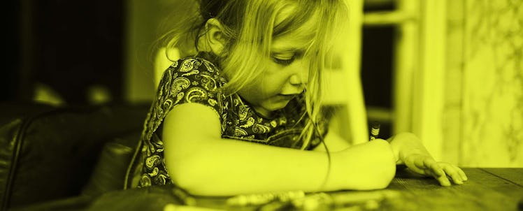 photo of child drawing with crayon at table