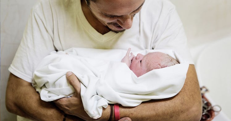 A father on paid family leave swaddles a baby