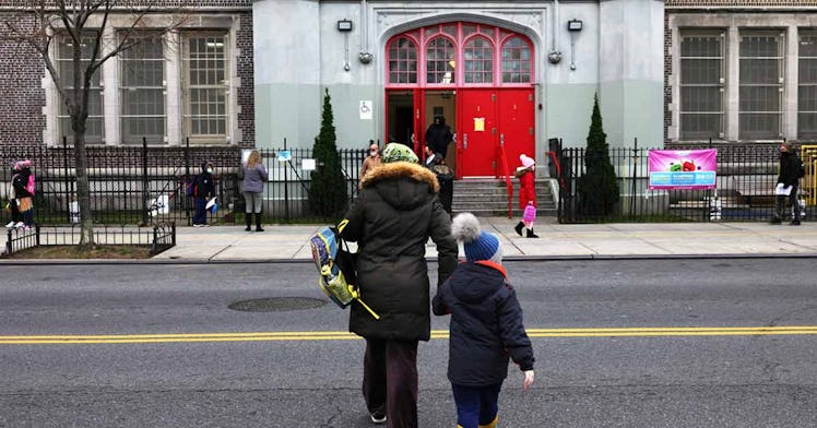 a woman holds onto a young boy and crosses the road