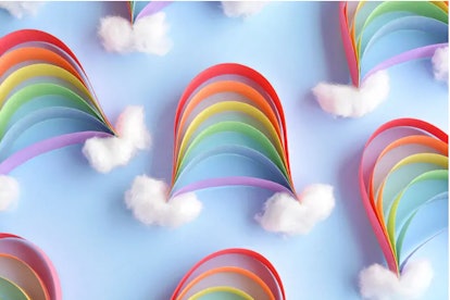 paper construction rainbows laying on top of blue background with cotton balls at either end to look...