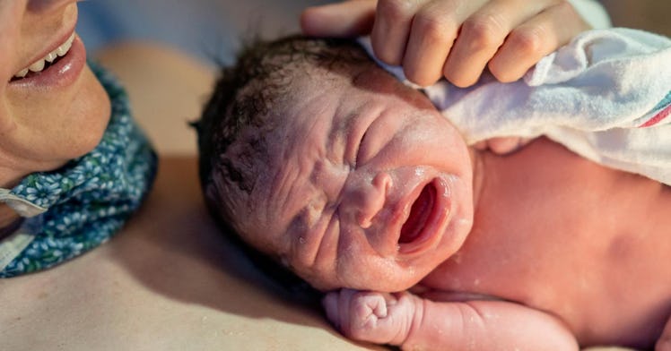 An infant cries on mom's chest