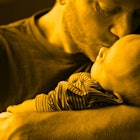A father kissing his son that has a rare, life threatening genetic condition