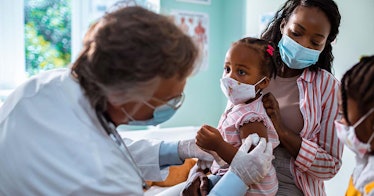A kid wearing a mask gets vaccinated
