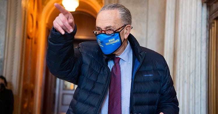 Senator Chuck Schumer wears a blue mask and points