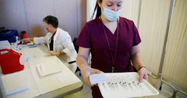 A nurse carries a tray of vaccine doses
