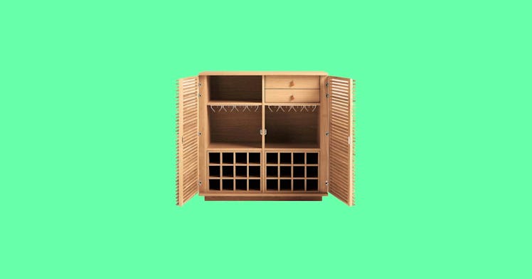 A liquor cabinet, also known as a liquor bar cabinet, set against a green backdrop.