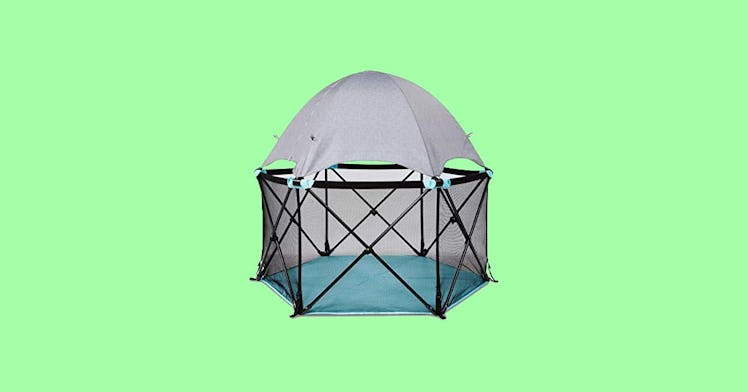 A portable play yard for kids, set against a green backdrop