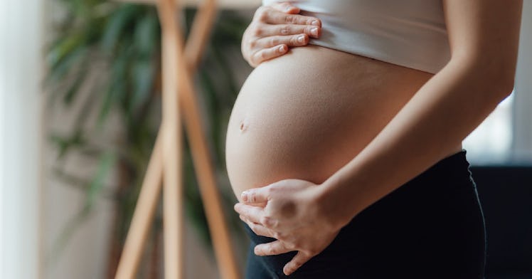 A pregnant person holding their baby bump.