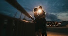 日落时分，男人和女人在桥上相互拥抱的画面
