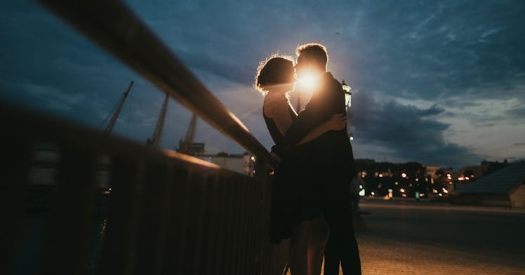 image of man and woman holding each other on a bridge at sunset