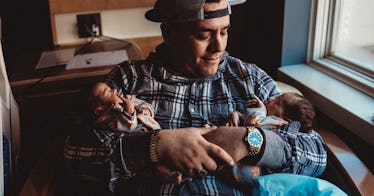 A new dad holds infant newborn twins