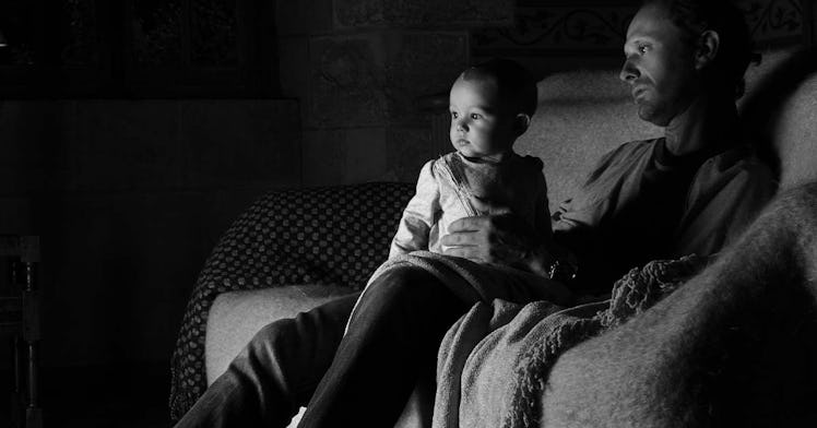 A kid and their dad sit in front of the television in black and white
