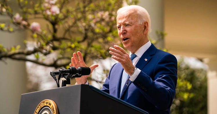 Biden speaks at a podium in front of a cherry blossom tree