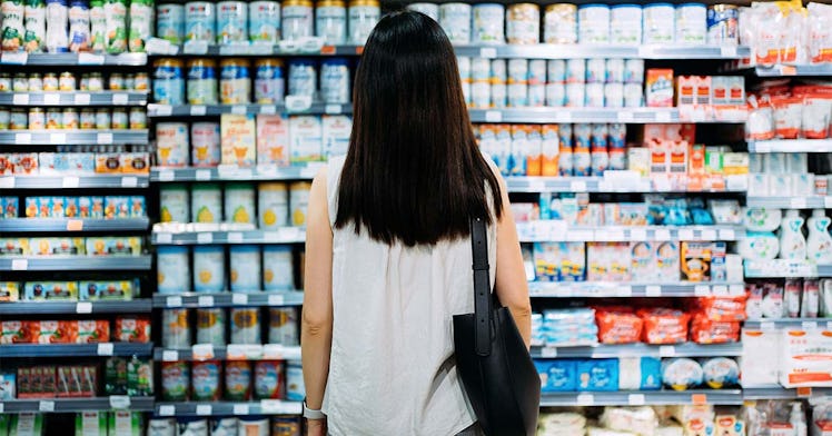 A woman stands in front of options at the grocery store