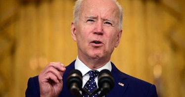Biden speaks at a podium in front of gold curtains