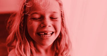 A smiling long haired child with a missing tooth