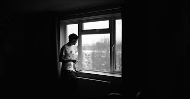 A man stares out of a window, alone, black and whtie image