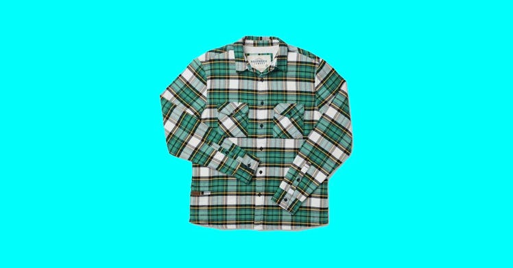 a green plaid men's shacket is pictured against a sky blue backdrop