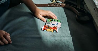 A child lining cars up in a line in a sunbeam