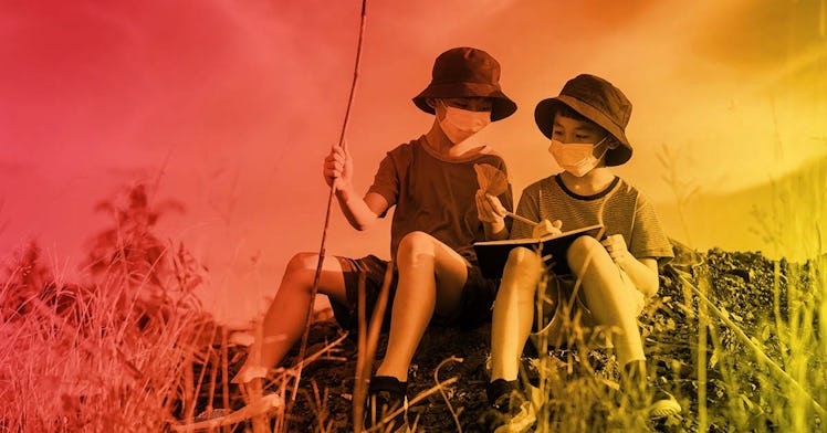 Two children sit on a rock outside