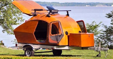 an all-wood diy teardrop camper parked on the grass beside the water