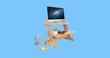 a bamboo standing desk convertor with two levels against a pale blue background