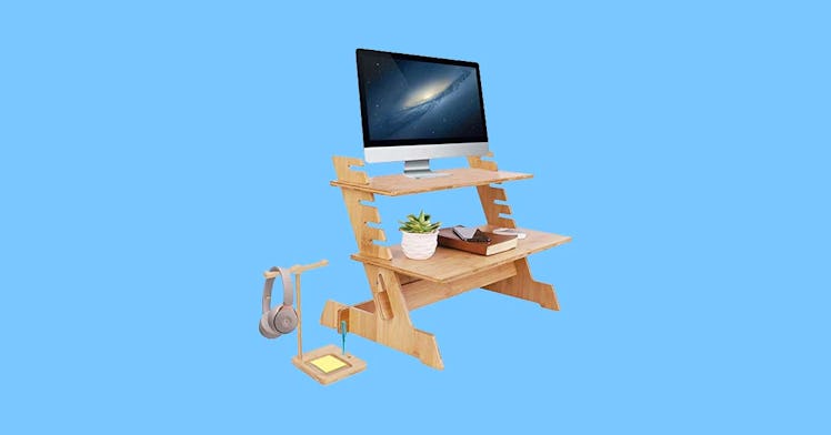 a bamboo standing desk convertor with two levels against a pale blue background