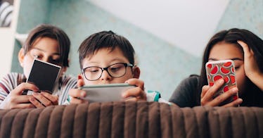 three children looking at cell phone screens