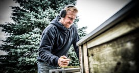 Father wearing 3M Worktunes hearing protection works in his backyard