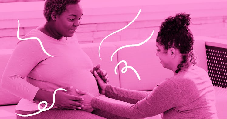 A Black expecting-mother has her pregnant belly touched by another Black woman