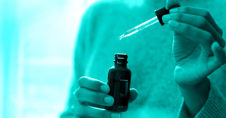 Closeup of hands taking a dropper from a dark essential oils bottle