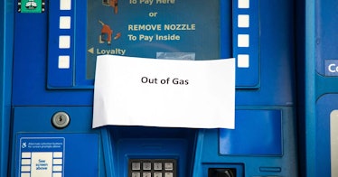 An empty blue gas pump with a sign that says 'out of gas'