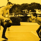 A father and a son playing basketball on a basketball court with a yellow color filter