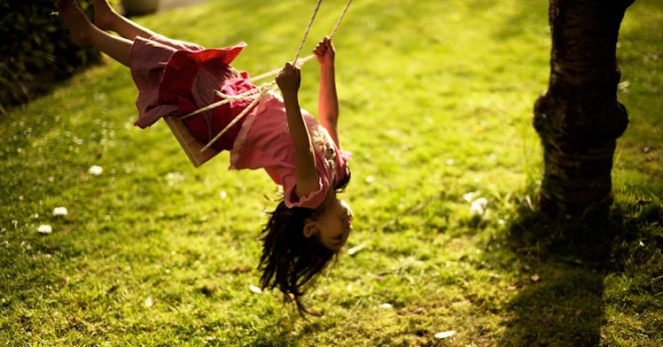 a kid wearing pink leans back in a swing, set against a background of green grass, depicting how to ...